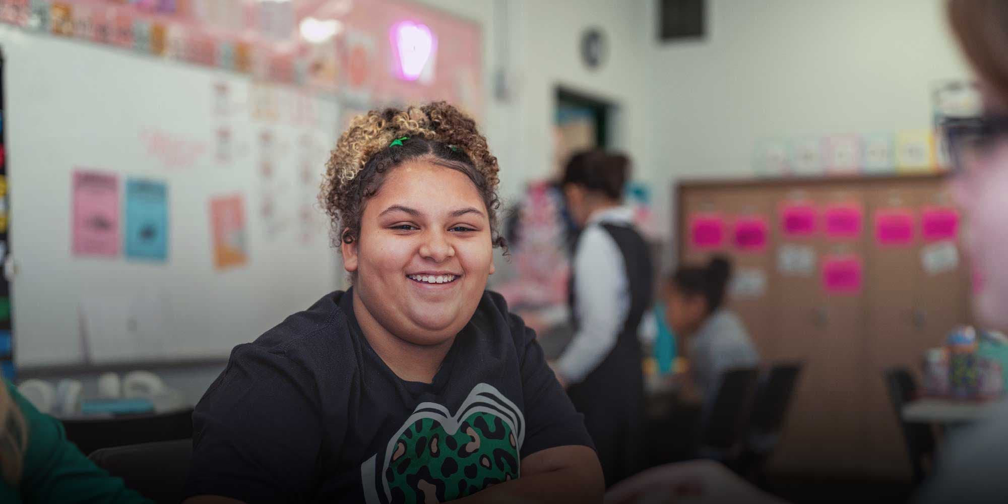 Smiling student sitting in a classroom.